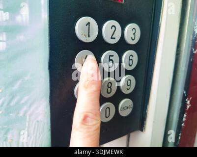 Close up of a finger pressing a metal button on an apartment entrance panel in Ors vezer tere Budapest. Concept of security, access, and urban living Stock Photo