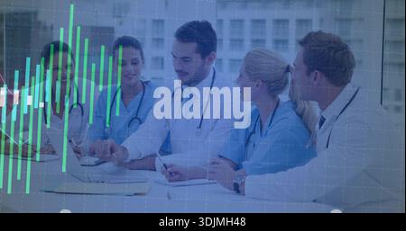 Discussing case, medical team in lab coats pointing at laptop in conference room, green chart Stock Photo