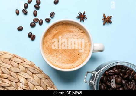 Cup of hot espresso and coffee beans on blue background Stock Photo