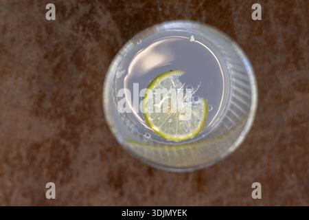 Refreshing cocktail drink in clear glass with fresh lime slice, seen from top view. Cool beverage or soda on marble table, simple and elegant refreshm Stock Photo
