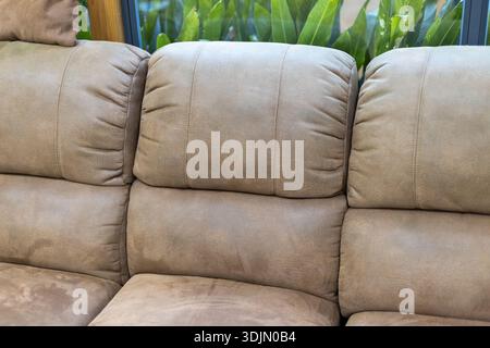 Close up of comfortable beige suede sofa back. This cozy furniture in living room provides relaxing background for interior design and home decoration Stock Photo
