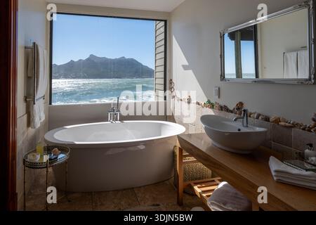 Relax in a beautifully designed bathroom featuring a soaking tub and breathtaking views of the ocean and mountains in Cape Town, South Africa. Perfect Stock Photo