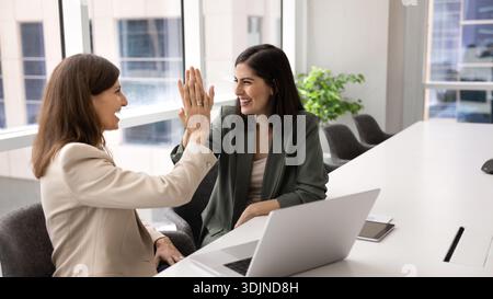 Two businesswomen giving high five gesture, celebrate joint task completion Stock Photo