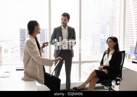Team leader clarifying project details during morning briefing with workmates Stock Photo