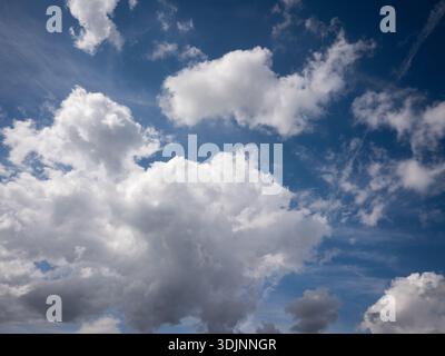 Bright white cumulus clouds in a deep blue summer sky, beautiful weather scenery during the daytime. Stock Photo