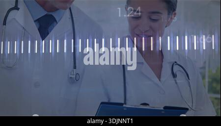Reviewing two doctors in lab coats with stethoscopes in clinic holding blue clipboard with waveform Stock Photo