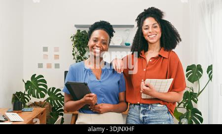 Two Friendly Women Colleagues Stand Together in a Modern Office, Smiling and Ready to Collaborate Stock Photo