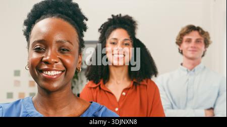 Three Friendly Colleagues in Office Smile While Working on Tech Project Stock Photo