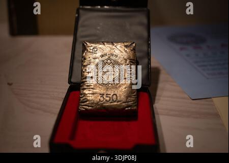 Commemorative metal ingot shaped like an Asland cement sack (1901-1976), displayed in a presentation box with red velvet lining. Stock Photo