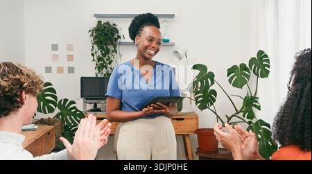 Smiling Woman Presenting in Modern Office While Team Applauds and Collaborates Stock Photo