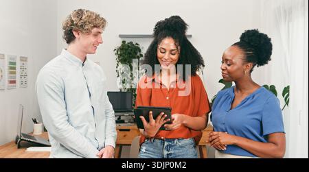 Trio Of Colleagues Collaborating In Modern Office With Tablet And Smiles Stock Photo