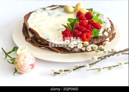 Holiday Easter greeting composition with cake, flowers, willow branch, and chocolate eggs. Stock Photo