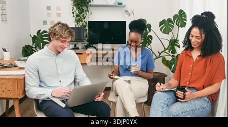 Trio Of Friends In Modern Office Collaborating On Laptop And Notes Stock Photo