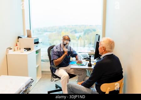 High angle view of male medical professional advising senior man while sitting in examination room Stock Photo