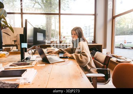 Focused mature female creative entrepreneur working on laptop in office Stock Photo