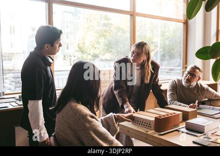Female creative professional discussing architect project with team in office Stock Photo