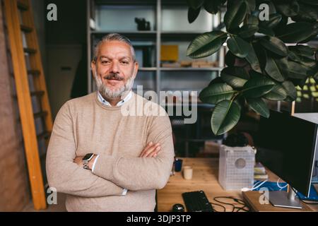 Portrait of confident mature male architect standing with arms crossed in office Stock Photo