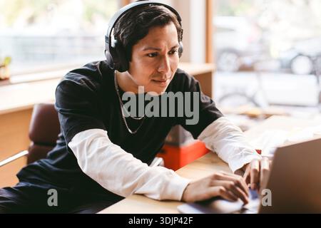 Focused male business expert wearing wireless headphones using laptop in office Stock Photo