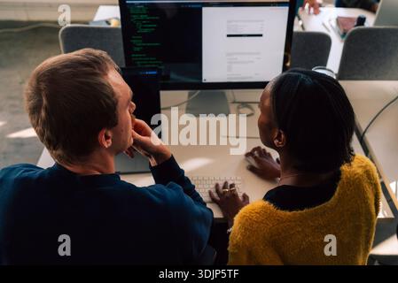 High angle view of male and female business professional working on computer at desk in tech office Stock Photo