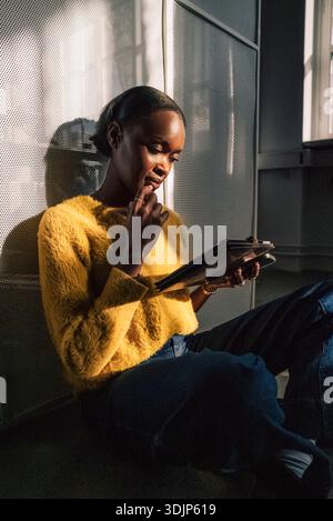 Concentrated female business expert using tablet PC while sitting on ground in startup office Stock Photo
