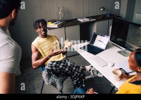 High angle view of male tech expert discussing with colleagues while sitting at desk in office Stock Photo