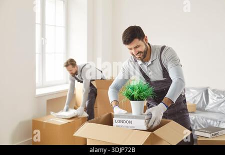 Smiling movers packing household items into boxes during efficient relocation Stock Photo