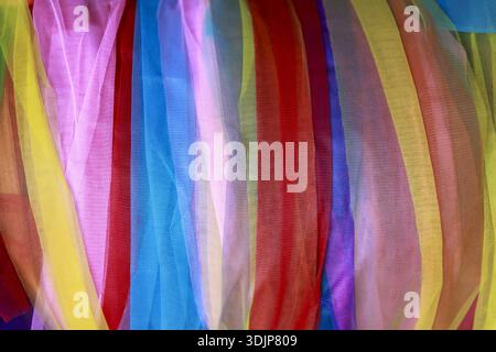 Vibrant, colorful background of abstract sheer fabric with vertical stripes. Flowing pink, yellow, and blue create joyful, delicate, and soft texture Stock Photo