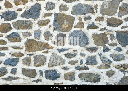 Background of a natural stone or sandstone masonry wall with cement in South France. Detailed stone texture image in beige, brown, grey and blue Stock Photo