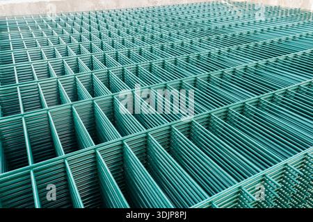 Selective focus on metal lattice fencing modules with green rectangular cells. Stock Photo