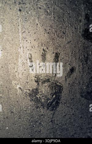 handprint on icy glass surface covered with frosty patterns Stock Photo