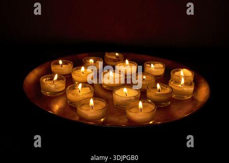 Burning candles in tea light glasses on a round metal tray Stock Photo