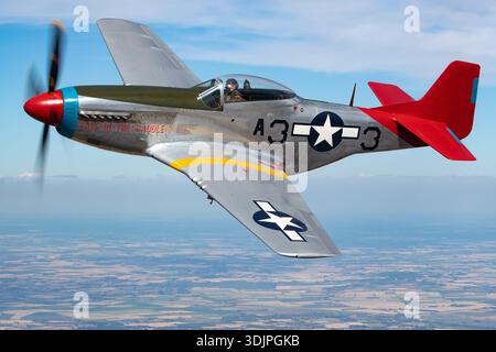 This close-up pilot view shows a North American F-51D Mustang, registration G-SIJJ, painted in U.S. Air Force display colors with the name Tall In The Saddle. The F-51D, also known as the P-51D Mustang, is a World War II-era single-seat fighter powered by a Packard V-1650-7 Merlin liquid-cooled V12 engine producing 1,490 hp, with a four-blade propeller. Airframe, cockpit, canopy, and wing details are visible during air-to-air flight at UK Warbirds 2022. Stock Photo