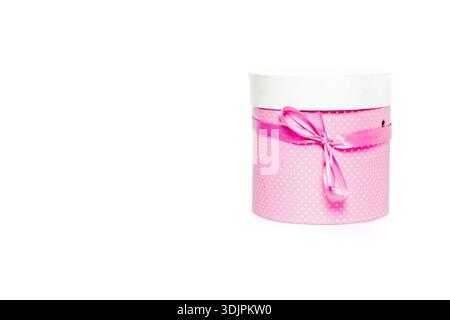 Round pink gift box with a white lid and ribbon, adorned with polka dots, isolated on a white background, suitable for various gifting occasions Stock Photo