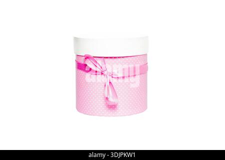 Round gift box in pink with a white lid and ribbon bow, decorated with polka dots, isolated against a white background for clear visibility Stock Photo