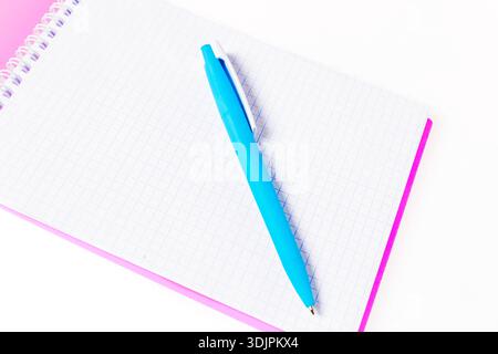 Blank grid notebook with a blue pen placed on top, showcasing a pink border, ideal for educational or office settings Stock Photo