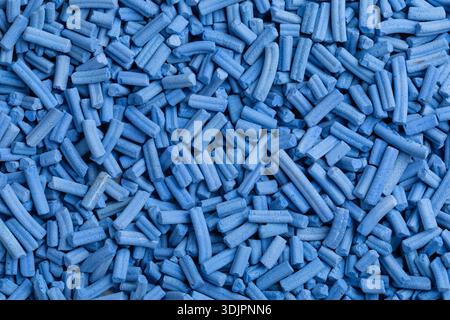 A top-down macro photo shows a dense, uniform layer of light blue cylindrical industrial catalyst pellets with a matte, porous texture. Stock Photo