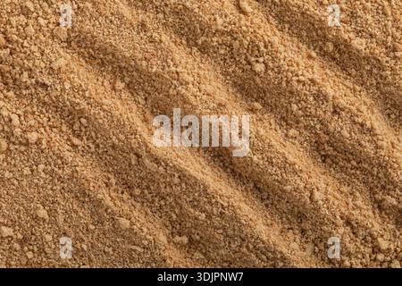 A high-angle macro photo of a nanostructured powder of medicinal herbs, showing the rough, uneven texture of a fine, dry, light brown or ochre-colored Stock Photo