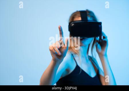 Female user interacting with virtual interface using VR headset, finger pointing gesture and immersive technology concept Stock Photo