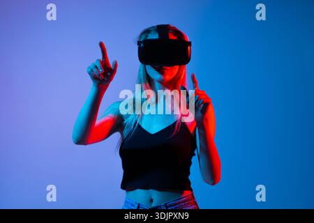 Futuristic virtual interaction with woman wearing VR headset and controlling digital interface with hand gestures Stock Photo