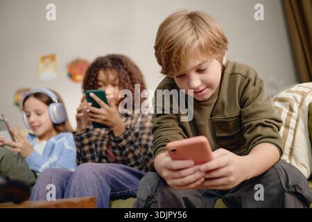 Generation Alpha Children Using Smartphones and Gadgets Indoors Together Stock Photo
