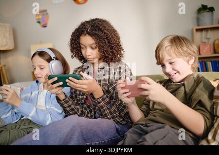Multiethnic Generation Alpha Children Using Smartphones Together Indoors Stock Photo