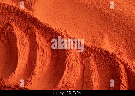 A top-down macro shot depicts a mass of vibrant orange nano electrostatic powder paint with visible ridges and smooth, fine-grained textures. Stock Photo