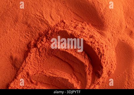 A top-down macro shot depicts a mass of vibrant orange nano electrostatic powder paint with visible ridges and smooth, fine-grained textures. Stock Photo