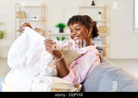 Happy African American Woman Doing Housework And Sorting Clean Laundry Stock Photo