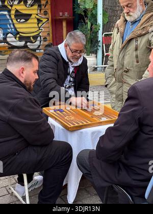 Men playing Tavli, the Greek version of Backgammon, at a street table near the antique shops of Avissinias Square, Athens, Greece. Local pastime. Stock Photo