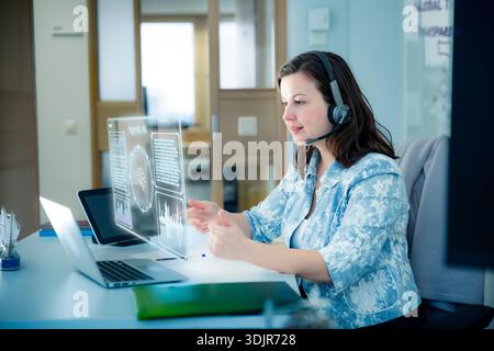 Professional woman interacts with agentic AI hologram and whiteboard. Innovation, future of work, and digital transformation concept. Real people. Stock Photo
