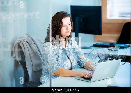 Professional woman interacts with agentic AI hologram and whiteboard. Innovation, future of work, and digital transformation concept. Real people. Stock Photo