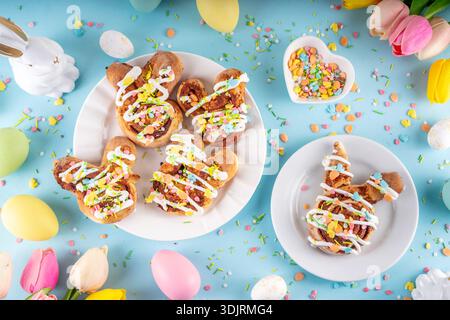 Cute and tasty Easter bunny cinnamon roll buns. Sweet bunny shaped buns, glazed and topped with colorful Easter sugar sprinkles, easter decorations, c Stock Photo