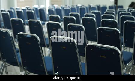 rows of empty blue chairs, arranged and prepared for an event, conference, or meeting. Stock Photo