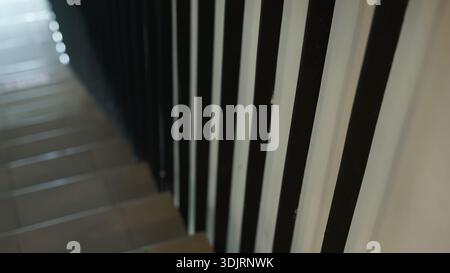 A modern interior staircase featuring a railing or banister made of vertical metal slats Stock Photo